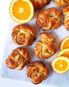 oranges and croissants are arranged on a cutting board next to an orange slice