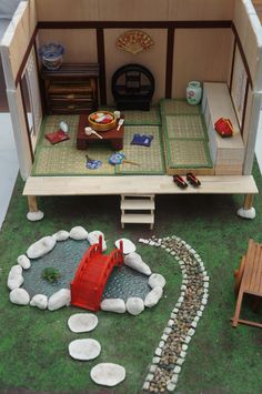 a doll house with furniture and accessories on the ground in front of a small garden