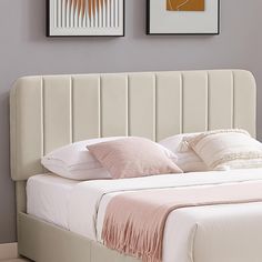 a white bed with two pictures above it