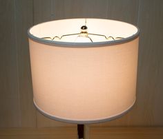 a lamp that is on top of a wooden table with a white shade over it