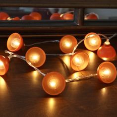 a bunch of orange lights sitting on top of a wooden table next to a mirror