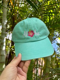 Embroidered 100% cotton low-profile dad hat with "Aloha" design and hibiscus flower center.  🧢Hat Details:  -100% Cotton - Unstructured Soft Crown Low-Fitting -Pre Curved Visor -Matching Fabric Under Visor -Metal Press Buckle 📏Size Details:  -Size: OSFM - Adult (58cm/22.8") -Low Profile: 8.25 cm - 8.4 cm / 3.2" - 3.3" 📦Shipping Details:  -all items ship in 1-2 business days 📱Follow us on Social Media:  -Instagram: @hifamilymaui -Facebook: @hifamilymaui Green Curved Bill Baseball Cap For Beach, Green Curved Bill Baseball Cap For The Beach, Cotton Curved Brim Baseball Cap For Vacation, Vacation Hats With Curved Bill In Cotton, Beach Green Cotton Baseball Cap, Green Cotton Baseball Cap For Beach, Green Baseball Cap For Vacation, Cotton Dad Hat For Vacation, Casual Flat Bill Dad Hat For Beach