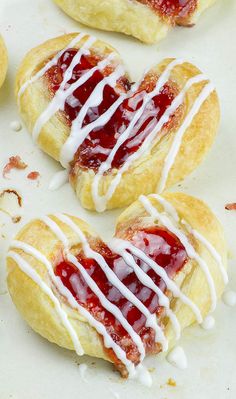 strawberry shortcakes with white icing are on a baking sheet and ready to be eaten