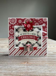 a christmas card with a red bow and poinsettis on it, sitting on top of a wooden table