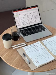 an open laptop computer sitting on top of a wooden table next to a cup of coffee