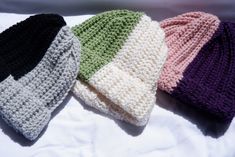 three crocheted hats laying on top of a white bed next to each other