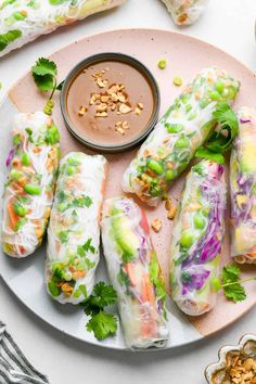 spring rolls on a plate with dipping sauce next to other appetizers and condiments