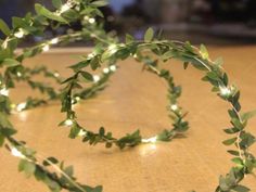 a bunch of green leaves that are on top of a wooden table with lights in the background