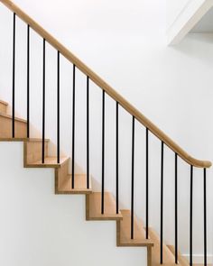 there is a wooden stair case with black railing on the top and bottom handrail