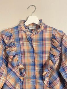 Vintage Private Line Plaid Ruffle Shirt! Pink/blue plaid print with long sleeves, ruffles along the chest, and buttons up the front. No size tag, but would best fit a medium, please refer to measurements. In excellent vintage condition! Approx. Measurements: Underarm to Underarm: 21" Sleeve Length: 23.5" Length: 25" Plaid Long Sleeve Blouse With Ruffles, Fall Plaid Top With Ruffles, Fall Plaid Ruffled Tops, Fall Button-up Ruffled Shirt, Fall Button-up Shirt With Ruffles, Casual Plaid Blouse With Ruffles, Fall Ruffle Button-up Shirt, Fall Ruffled Button-up Shirt, Blue Long Sleeve Ruffled Shirt