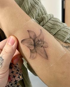 a woman with a tattoo on her arm holding onto a piece of paper that has a flower on it