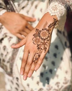 a woman's hand with a henna tattoo on her left wrist and flowers on the