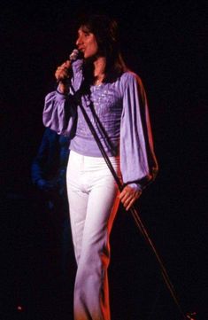 a woman in white pants holding a microphone