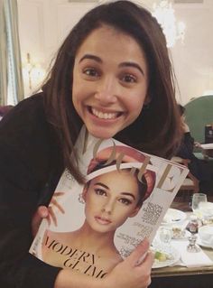 a woman is holding up a magazine with an image of her face on the cover