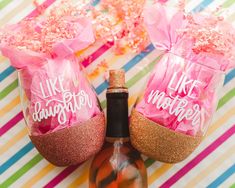 two wine glasses decorated with pink and gold confetti sitting next to each other