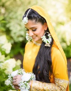 a woman in yellow is holding flowers and smiling