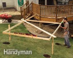 a man standing next to a wooden structure in the middle of a grass covered yard