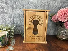 a wooden box with a key hole on it and flowers in the vase next to it