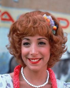 a woman with red hair wearing a necklace and smiling