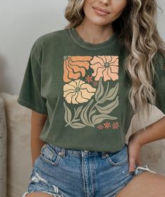 Looking for a comfortable and stylish t-shirt that shows off your love for flowers and nature? Our floral t-shirt with a beautiful wildflowers aesthetic print is the perfect choice! Featuring a stunning print of wildflowers in a gorgeous, natural setting, this t-shirt is perfect for anyone who loves spending time outdoors and appreciates the beauty of nature. The colors are vibrant and eye-catching, and the print is sure to attract compliments wherever you go. Made from high-quality materials, t Trendy Green Floral Print Shirt, Trendy Short Sleeve Shirt With Plant Print, Green Graphic Tee With Plant Print, Green Graphic Tee With Plants Print, Green Short Sleeve Tops With Plant Print, Green Short Sleeve Shirt With Plant Print, Green Tops With Plant Print Short Sleeves, Trendy Green Tops With Front Print, Green Floral Print Tops With Relaxed Fit