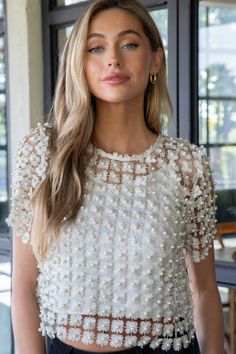 Add a playful touch to your wardrobe with the Laurel Crochet Lace Pearl Beaded Top. This cream-colored top features elegant crochet lace and stunning pearl beading, while the sheer fabric adds a touch of femininity. The back button neck detail and short sleeves complete this cropped top for a fun and flirty look. General Info: 100% Polyester Hand Wash Cold; Hang Dry Crochet Lace Pearl Beaded Sheer Outer Cami Lining Included Back Button Neck Detail Short Sleeves Cropped Fit Guide: Shape & Fit: Re White Crochet Top With Lace Trim For Party, Fitted Summer Blouse With Pearl Embroidery, Fitted Pearl Embroidered Blouse For Summer, Embellished Fitted Mesh Top For Spring, Lace Mesh Top For Spring Party, Elegant Beaded Tops For Spring, Elegant Crew Neck Mesh Top For Spring, Feminine Fitted Crochet Top For Party, Pearl Embroidered Evening Top For Spring