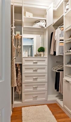 a walk in closet with white drawers and shelves