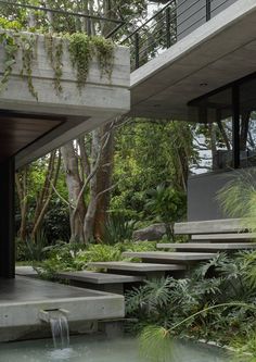 an outdoor area with water features and stairs leading up to the upper level, surrounded by greenery