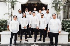 a group of men standing next to each other in front of a white building with palm trees