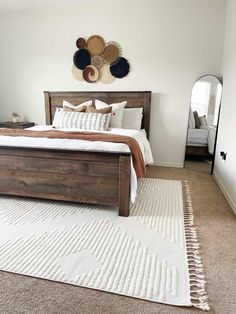 a bedroom with a bed, mirror and rug