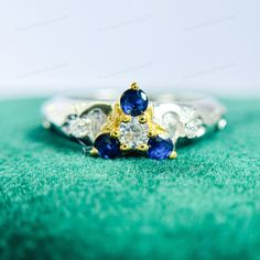 an engagement ring with two blue and white stones on top of green velvet covered surface