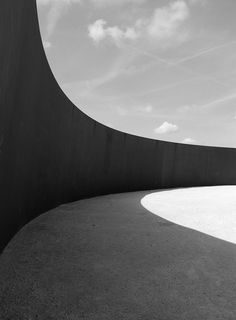 a man riding a skateboard down the side of a cement wall under a cloudy sky