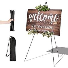 a wooden welcome sign next to a black bag and some other items that include an umbrella