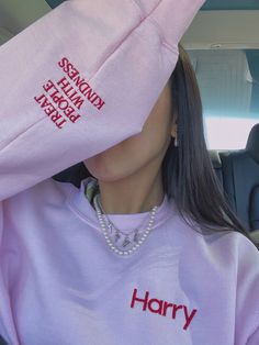 a woman wearing a pink sweatshirt with the words harry on it