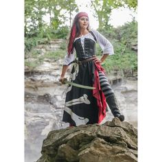 a woman in a pirate costume standing on top of a rock