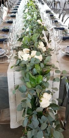 a long table with white flowers and greenery