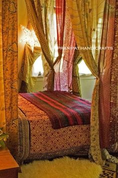 a canopy bed in a bedroom with curtains on the sides and a rug on the floor