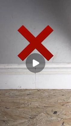 a red x sign is on the floor in front of a white wall with a black arrow pointing to it