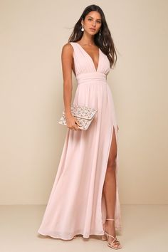 a woman in a long pink dress with a slit down the side and a white clutch on her hip