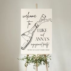 a welcome sign is displayed on an easel in front of a white wall with greenery