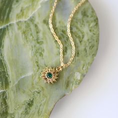 "Beautiful and lovely tiny gold sun pendant necklace. Made of tiny emerald green cubic stone gold sun charm with a skinny gold plated brass chain. Soft and simple. Great for gift, everyday or special occasion. Your item will ship in a gift box. Please feel free to contact me if you have any question. ♥ Length 14\" - 20\" chain ♥ Sun charm 1/2\" ♥ Gold plated over brass/ Emerald Green Cubic Zirconia ♥ See more Rudiana Accessories Rudiana.etsy.com" Dainty Clavicle Chain Necklace For May Birthstone, Dainty Emerald Gold Necklace, Green Dainty Necklaces With Charms, Gold Charm Necklace With May Birthstone, Dainty Gold Necklace With Emerald, Dainty Green Necklace With Charms, Gold Charm Necklace With Adjustable Chain For May Birthstone, Green Dainty Necklace With Charms, Dainty Green Charm Necklace With Round Pendant