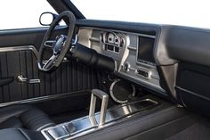 the interior of a classic car with black leather and chrome trims, including steering wheel