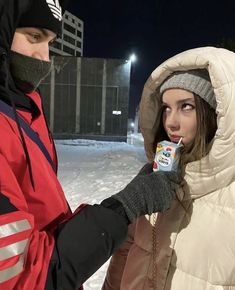 a man and woman standing in the snow with an ice cream carton on their finger