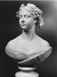 black and white photograph of a bust of a woman with flowers in her hair, looking to the side