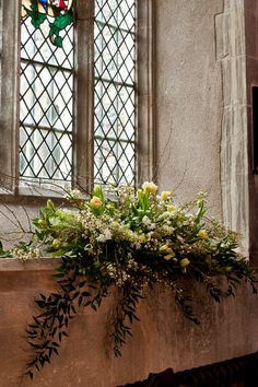 a window sill with flowers in front of it and a stained glass window behind it