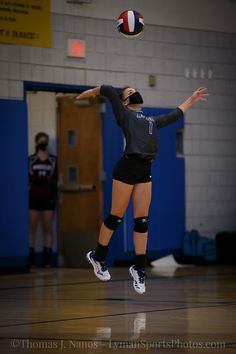 a woman jumping up to hit a volleyball