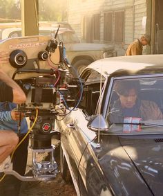 a man sitting in front of a car with a camera attached to it