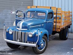 an old blue truck parked in front of a building