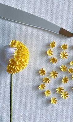 some yellow flowers and a knife on a white table cloth next to the cutting board