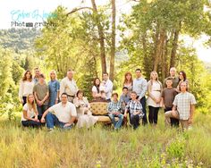 a large group of people posing for a photo in the grass with trees behind them