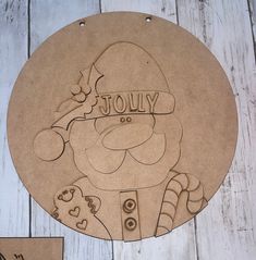 a wooden plaque with the words jolly on it and an image of santa claus holding a candy cane